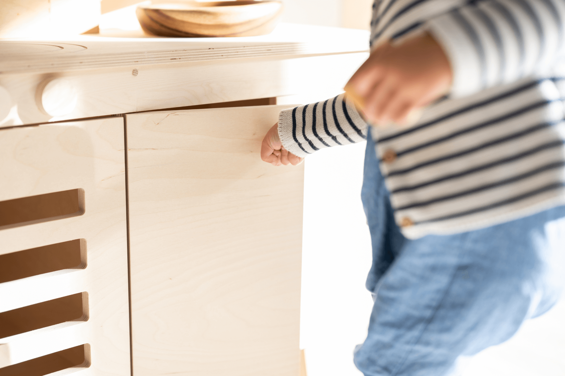 A child opens the door of a play kitchen