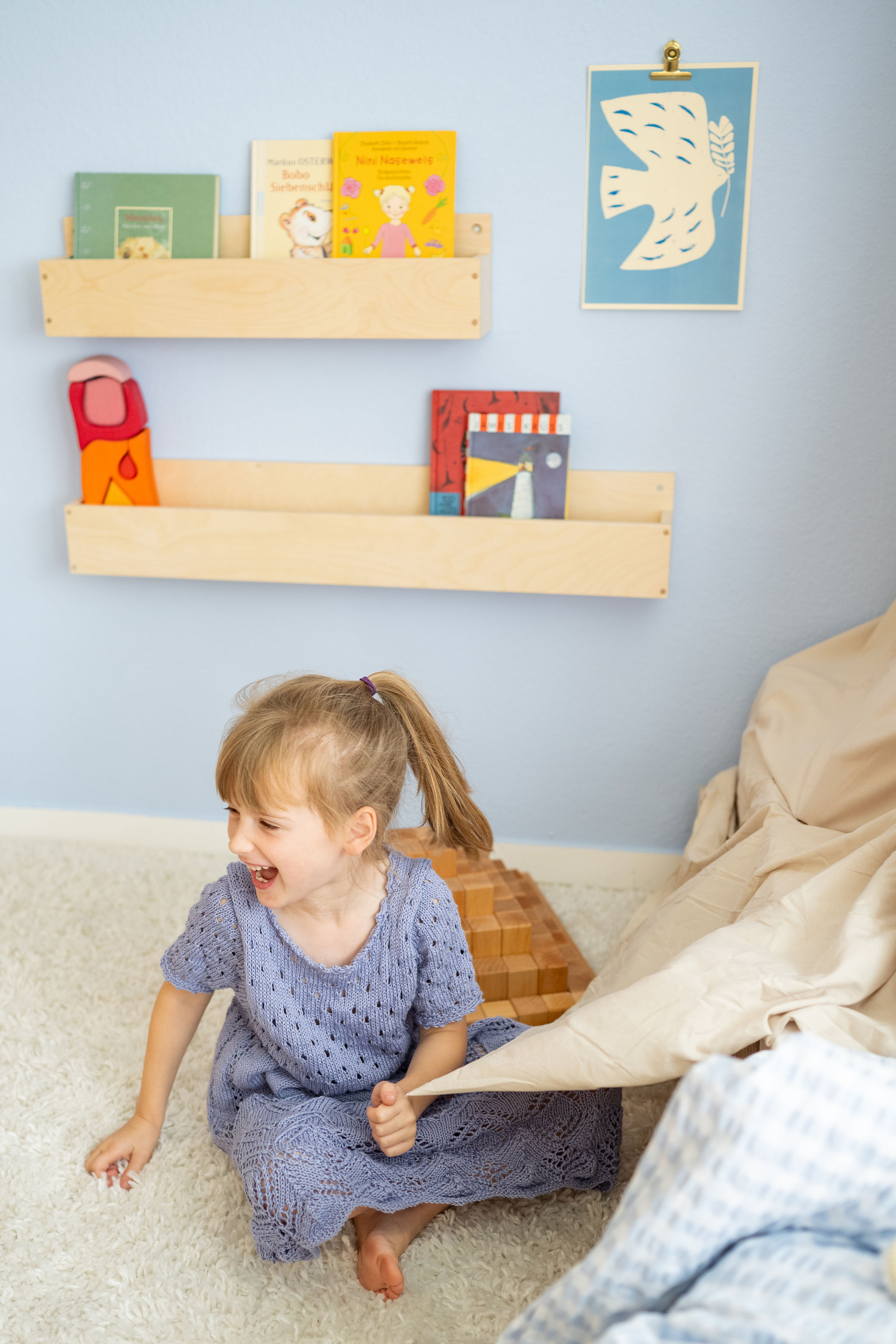 Mädchen sitzt auf dem Boden und lacht vor Bücherregalen