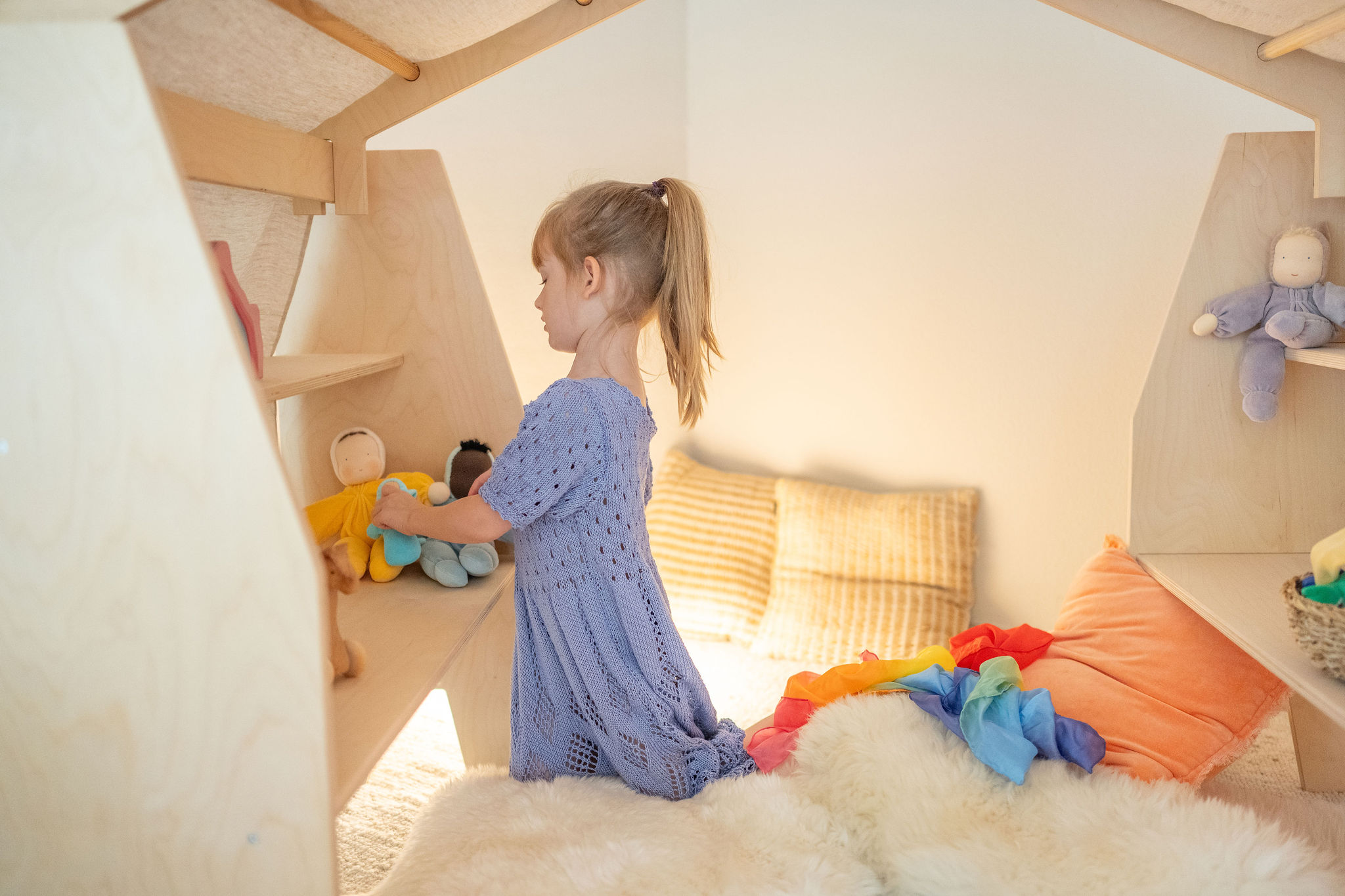 Mädchen spielt mit Puppe in Spielhöhle