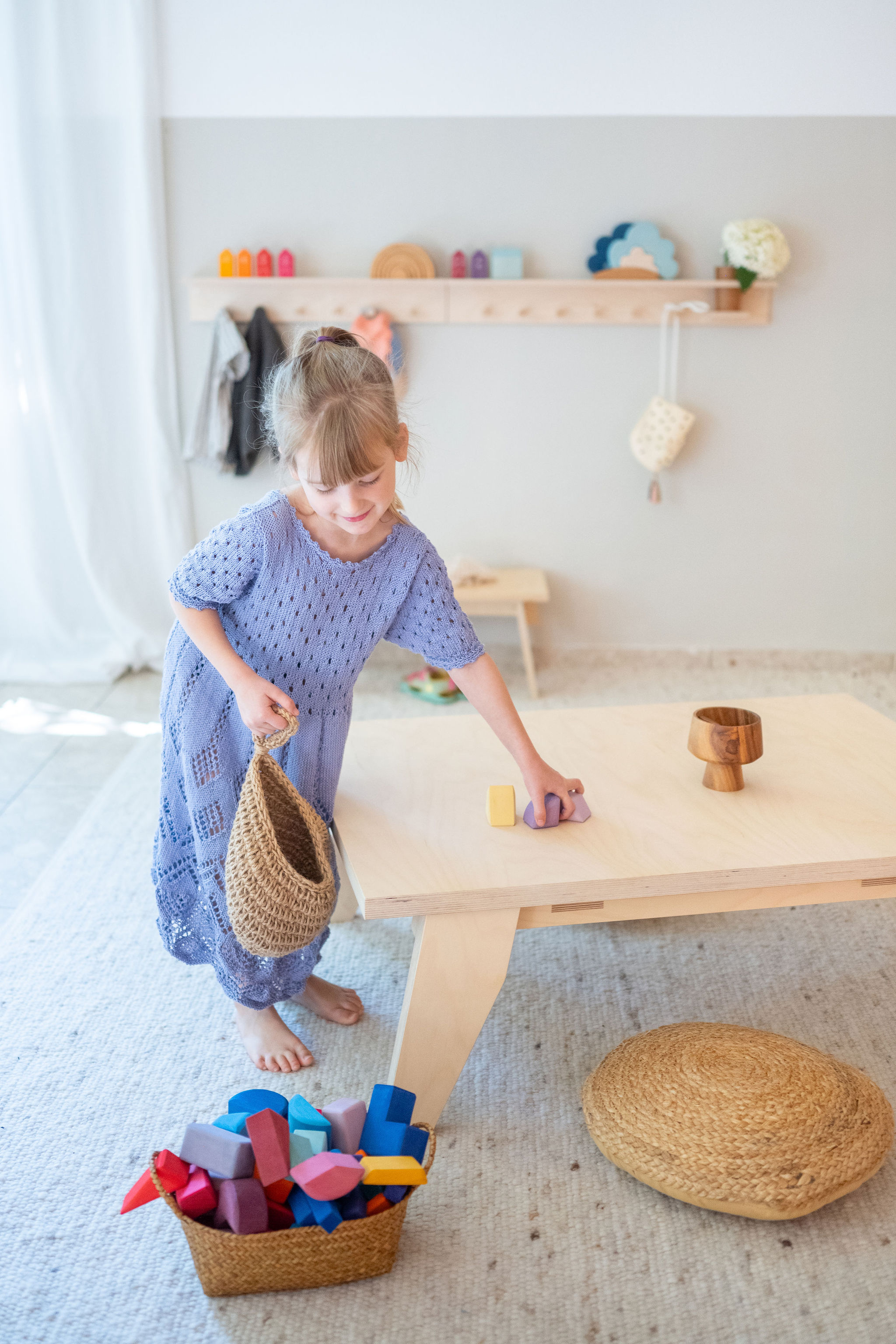 Mädchen räumt Holzspielzeug von einem Tisch