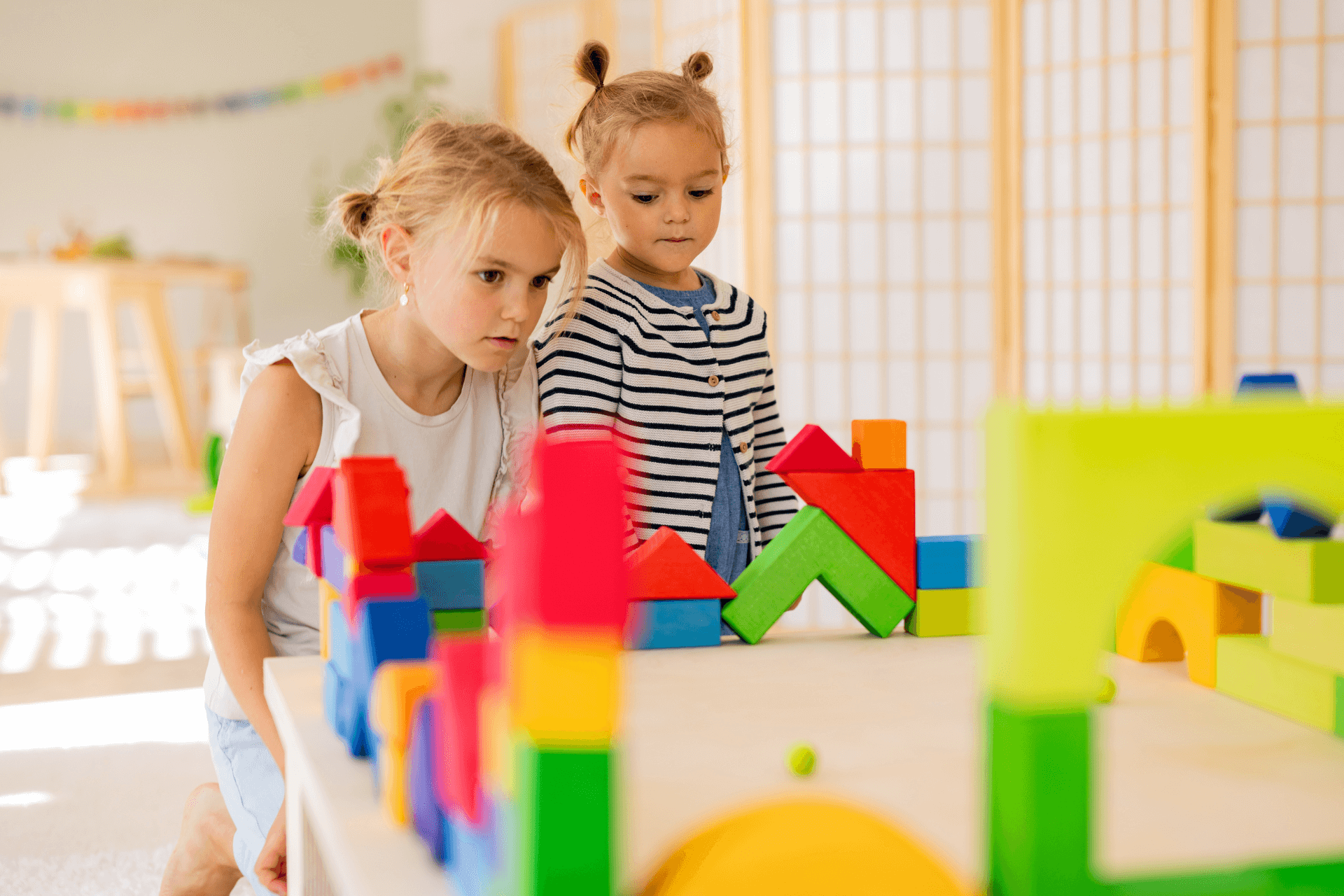 Two girls playing with colourful wooden blocks