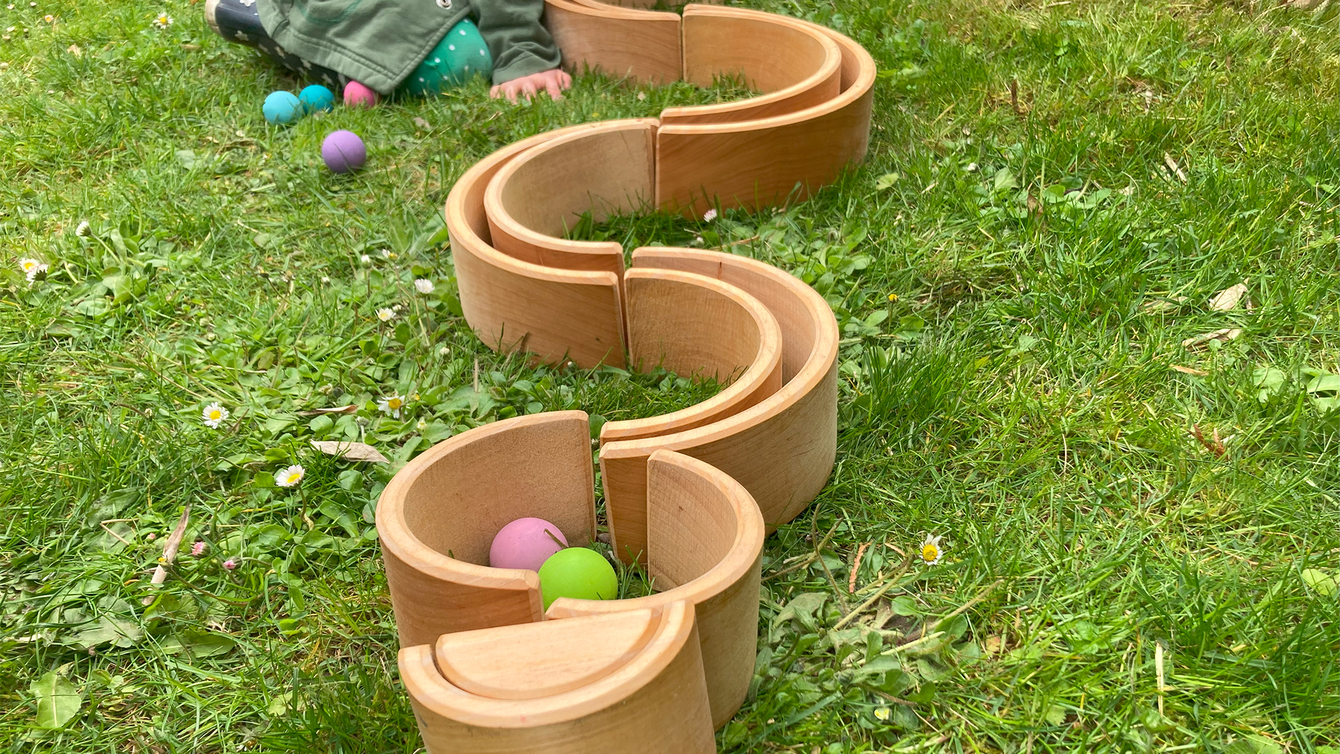 Holzkugeln werden von einem Kind eine Holzkugelbahn entlang gekugelt.