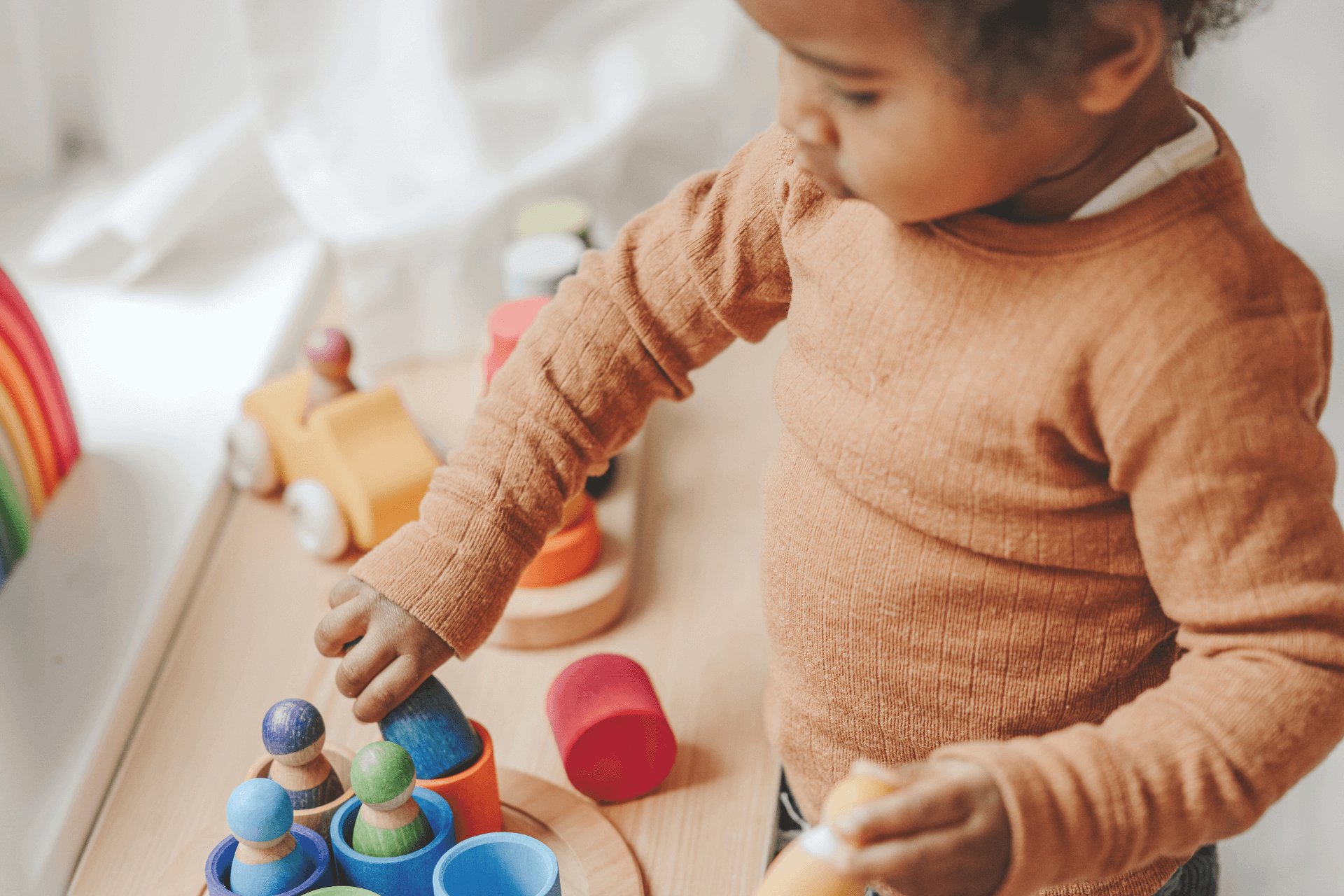 A toddler plays with wooden figures and bowls